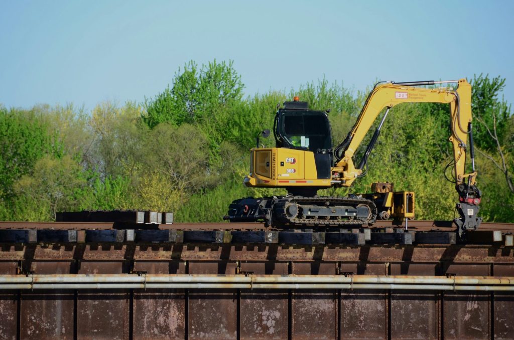 ein gelber Bagger, der auf einem Bahngleis steht