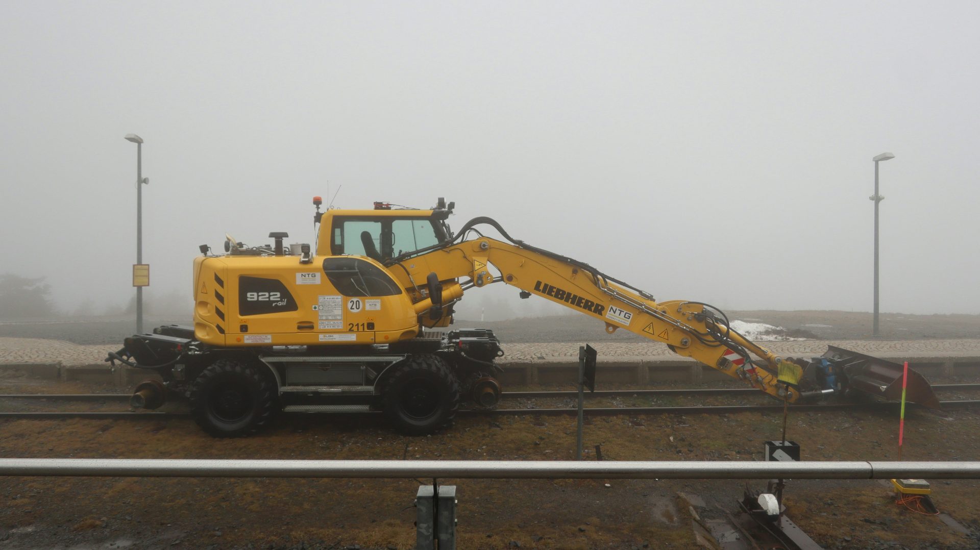 Ein gelber Traktor steht auf den Gleisen.